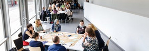 Personen sitzen an Tischgruppen
